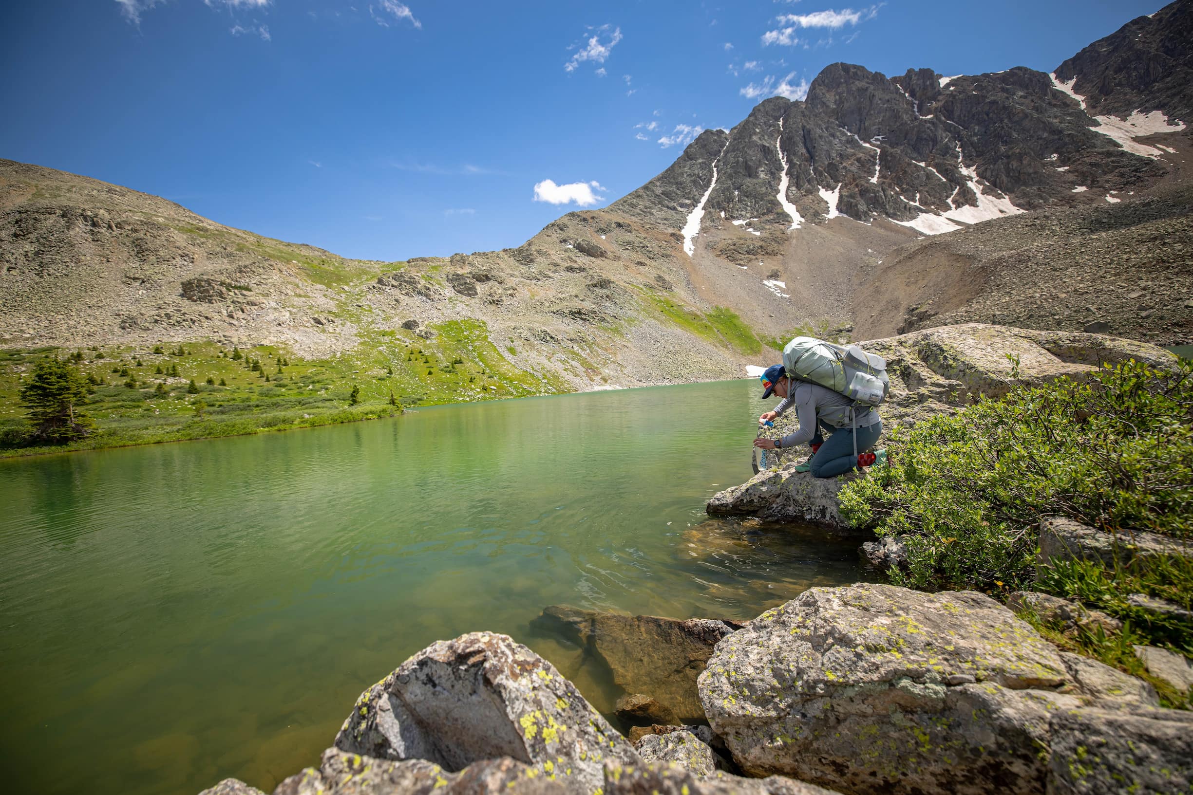 kneeling next to an alpine lake