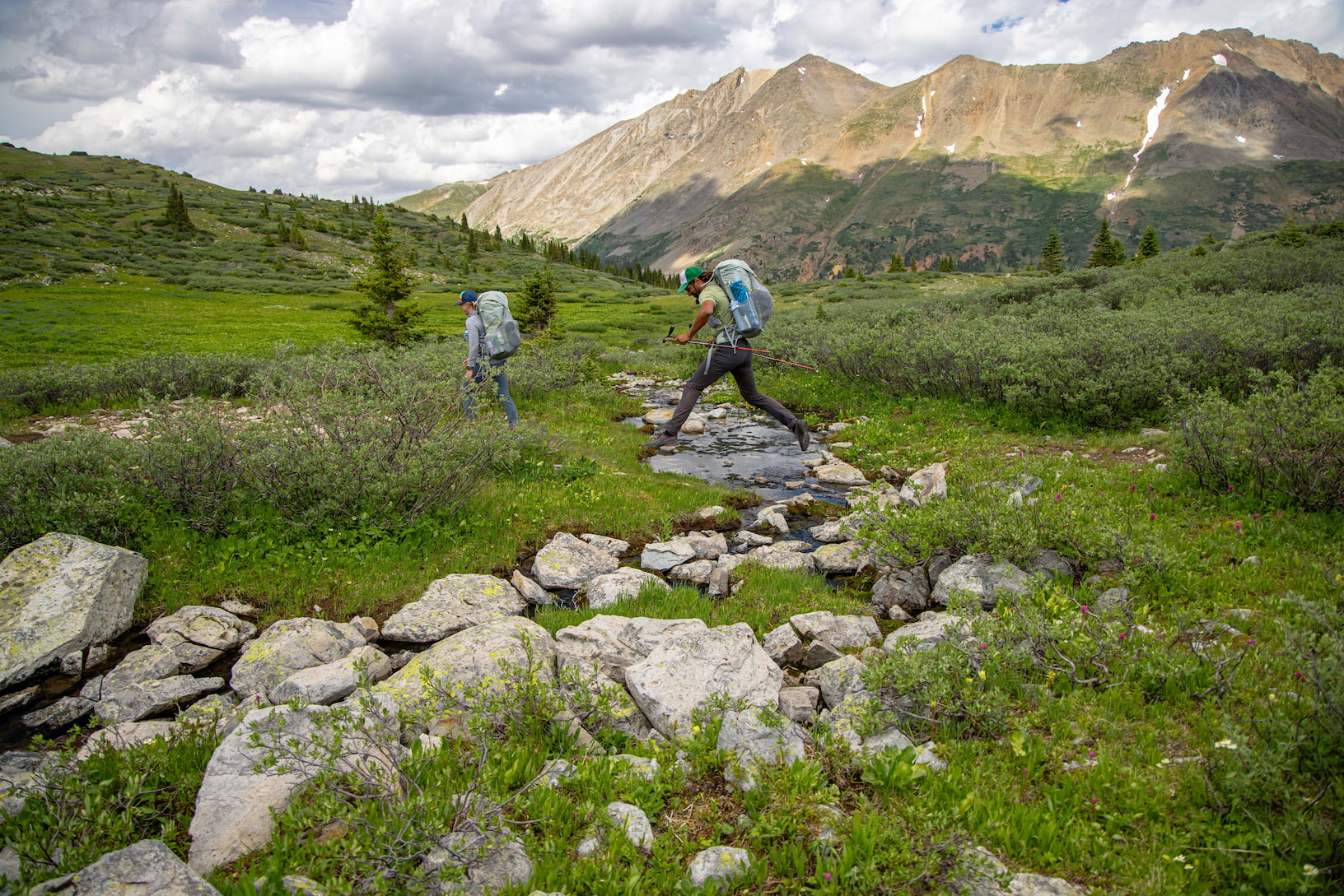 leaping across a stream wearing an ultralight backpack