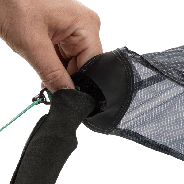 A close-up of a hand tying a green string to the end of the black and gray String Ridge VST 1.5 by Big Agnes, highlighting its detailed fabric and handle—ideal for assembling ultralight shelters or VST tents on your outdoor trips.