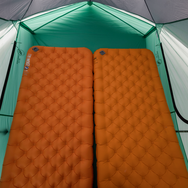 Two orange camping mattresses inside a tent