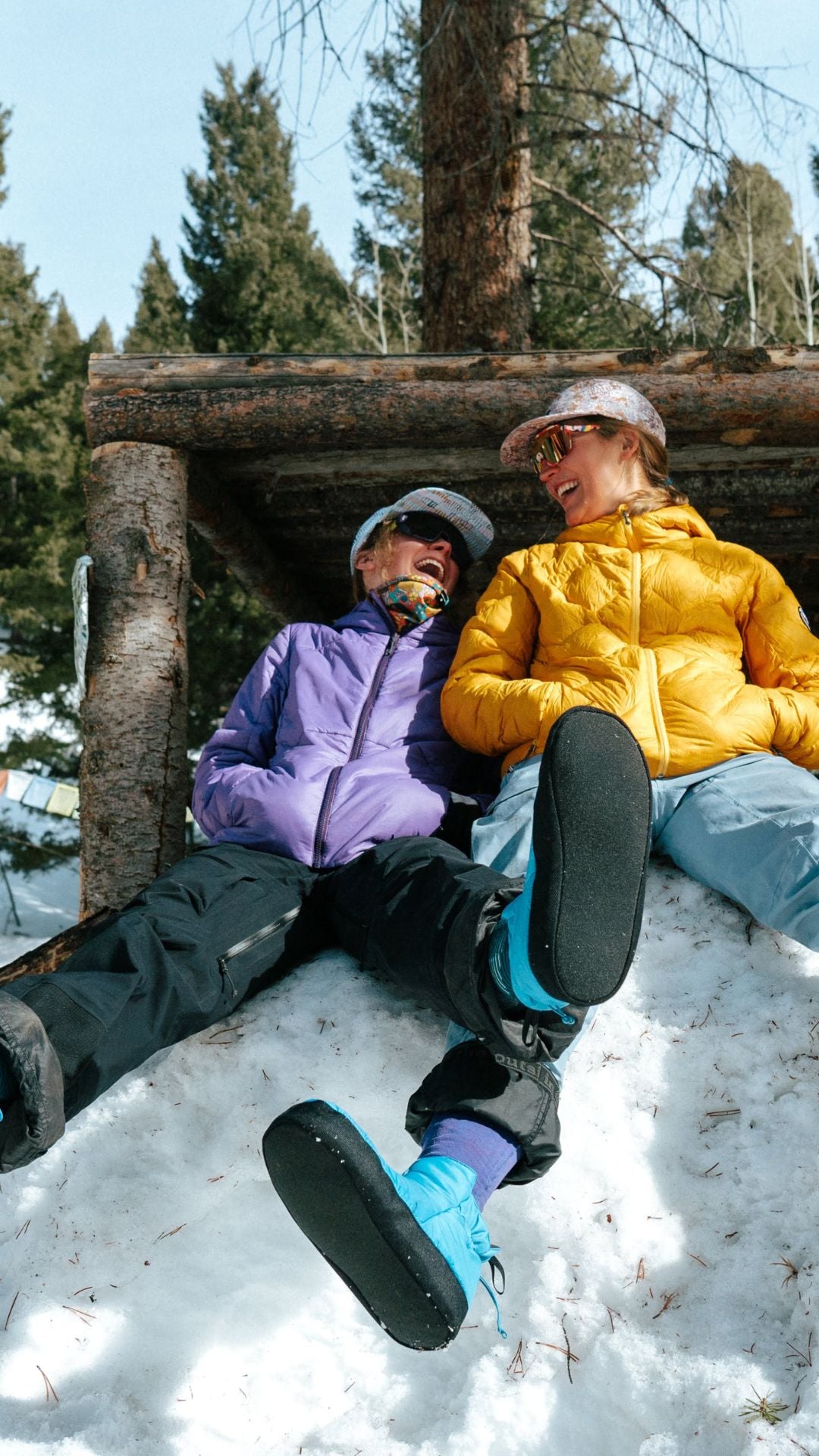 Two people sitting on a log in a snowy forest